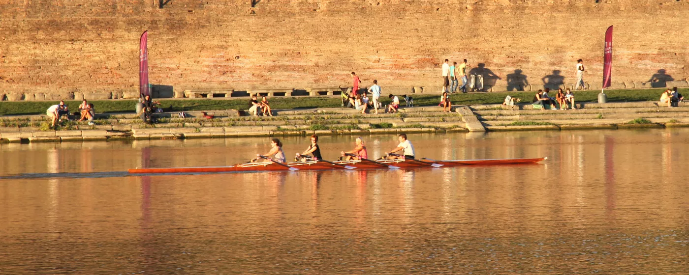 Quatre rameurs de loisir en aviron de couple sur la Garonne à Toulouse, dans la lumière du soir