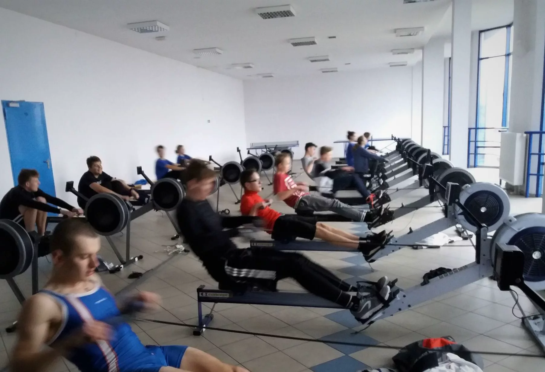 Jeunes rameurs en séance d'ergomètre, alignés en rangée dans une salle d'entraînement