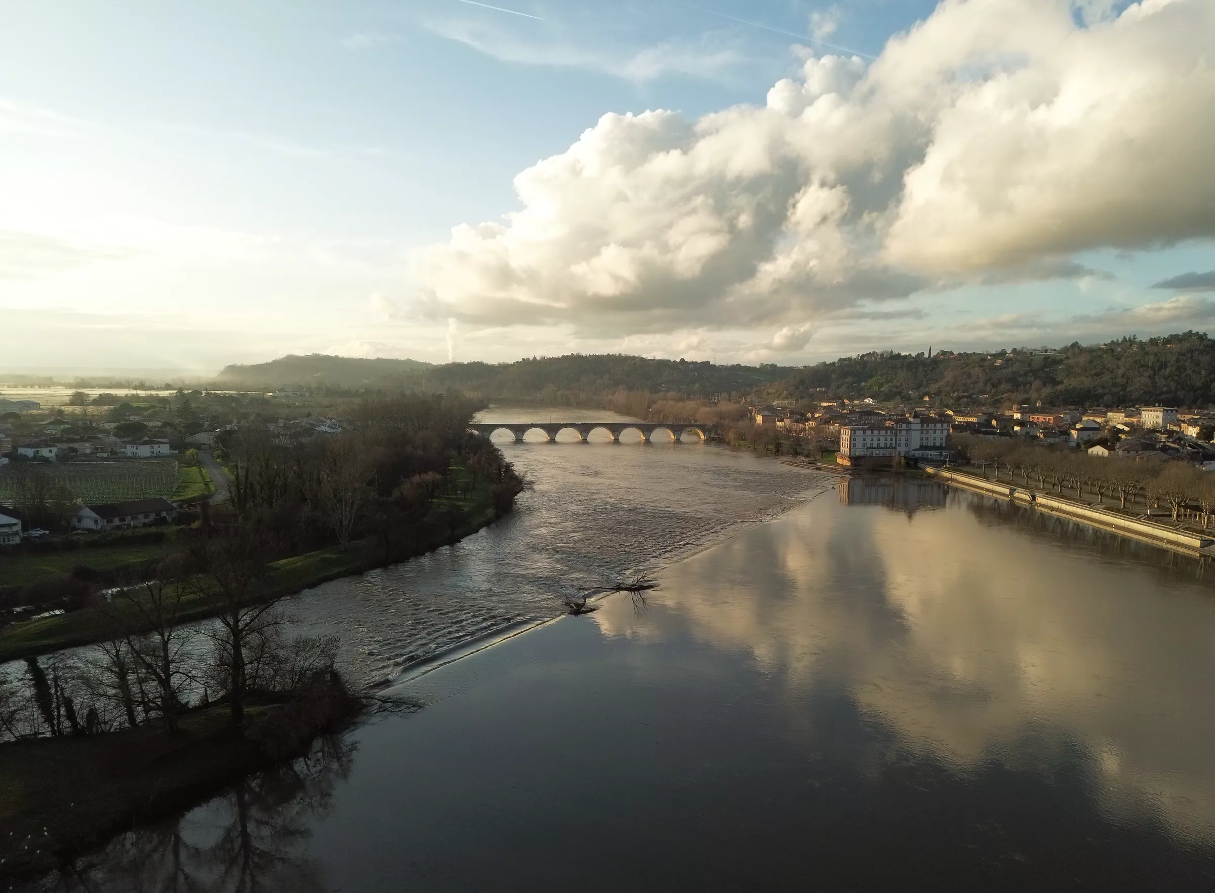 Le Tarn à Moissac vu du ciel, avec le pont et les quais de la ville sous un ciel nuageux